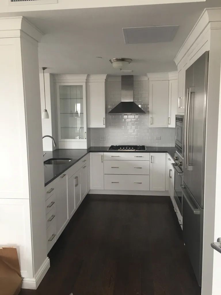 A kitchen with white cabinets and black counter tops