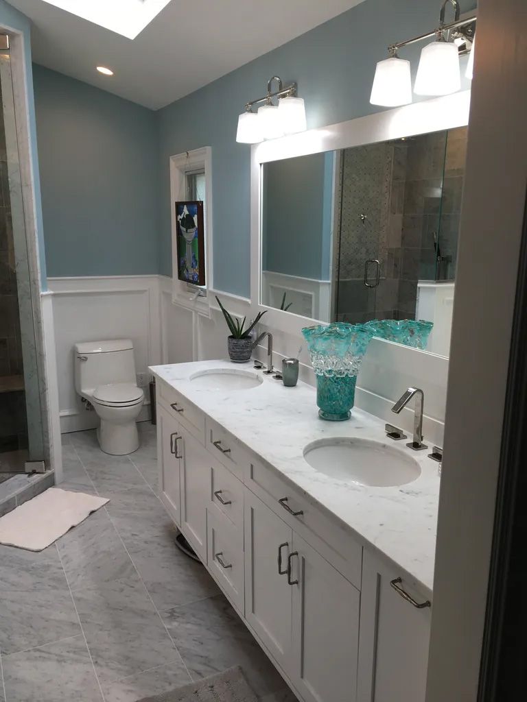 A bathroom with two sinks , a toilet , and two mirrors.