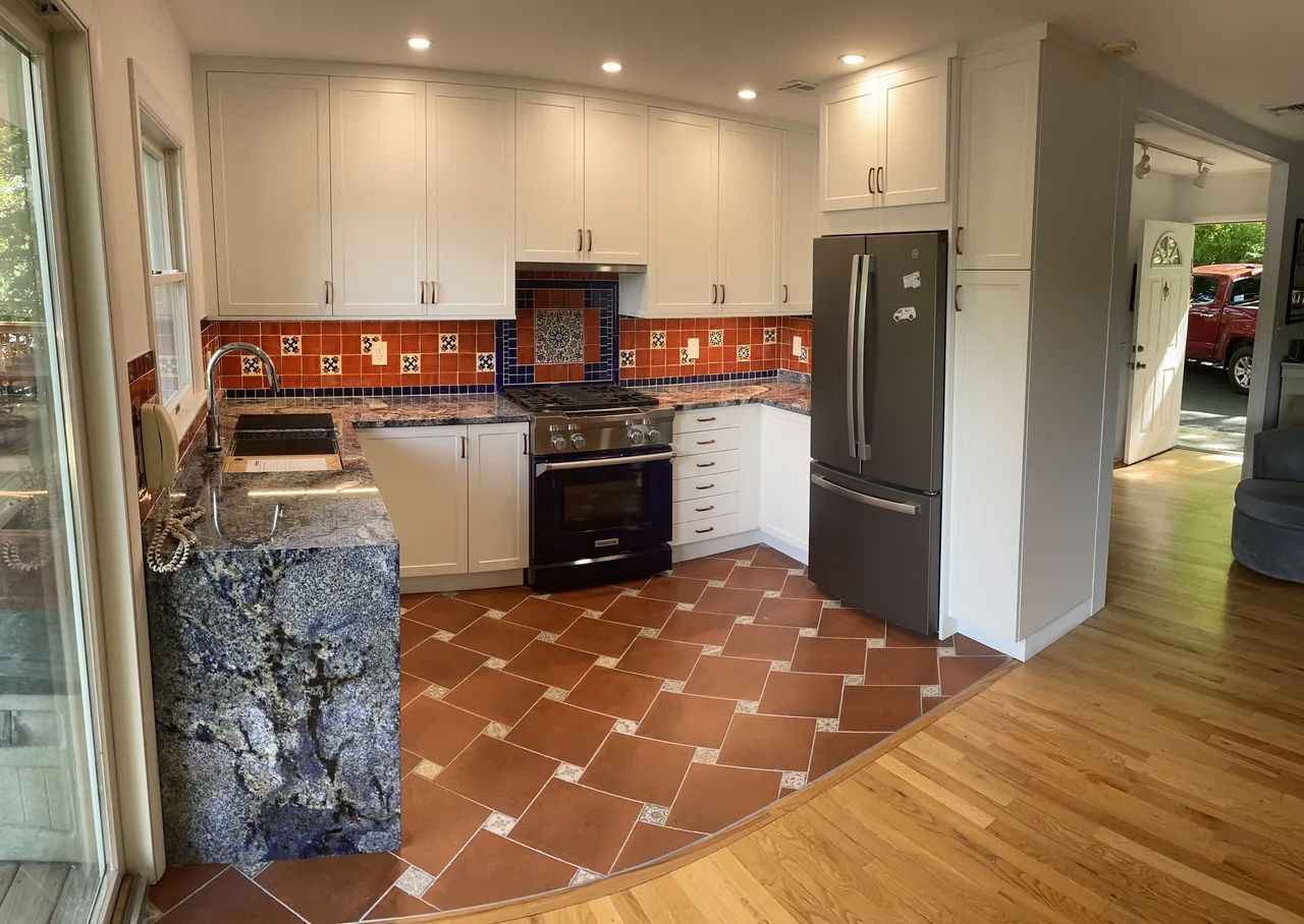 A kitchen with white cabinets , a refrigerator , a stove , and a sink.