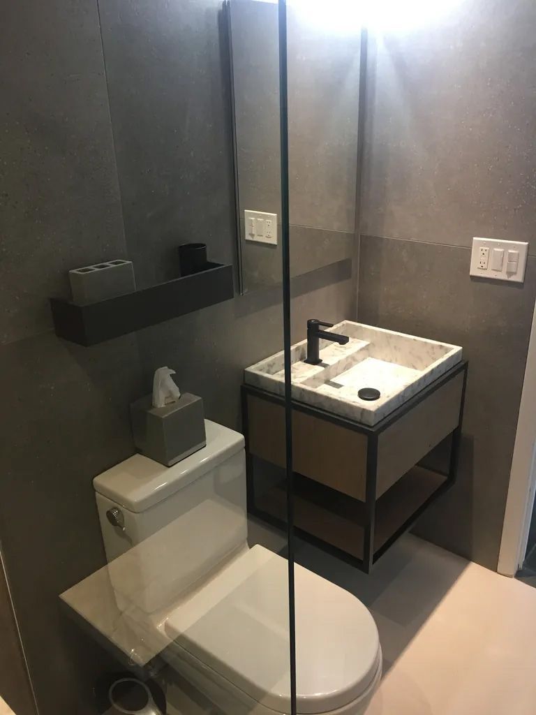 A bathroom with a toilet , sink and mirror.
