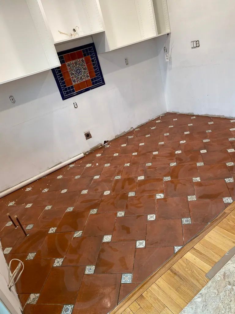 A kitchen with a tiled floor and white cabinets.