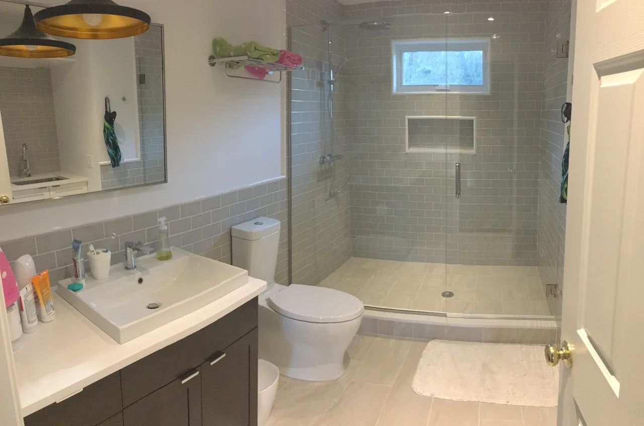 A bathroom with a toilet , sink and shower.