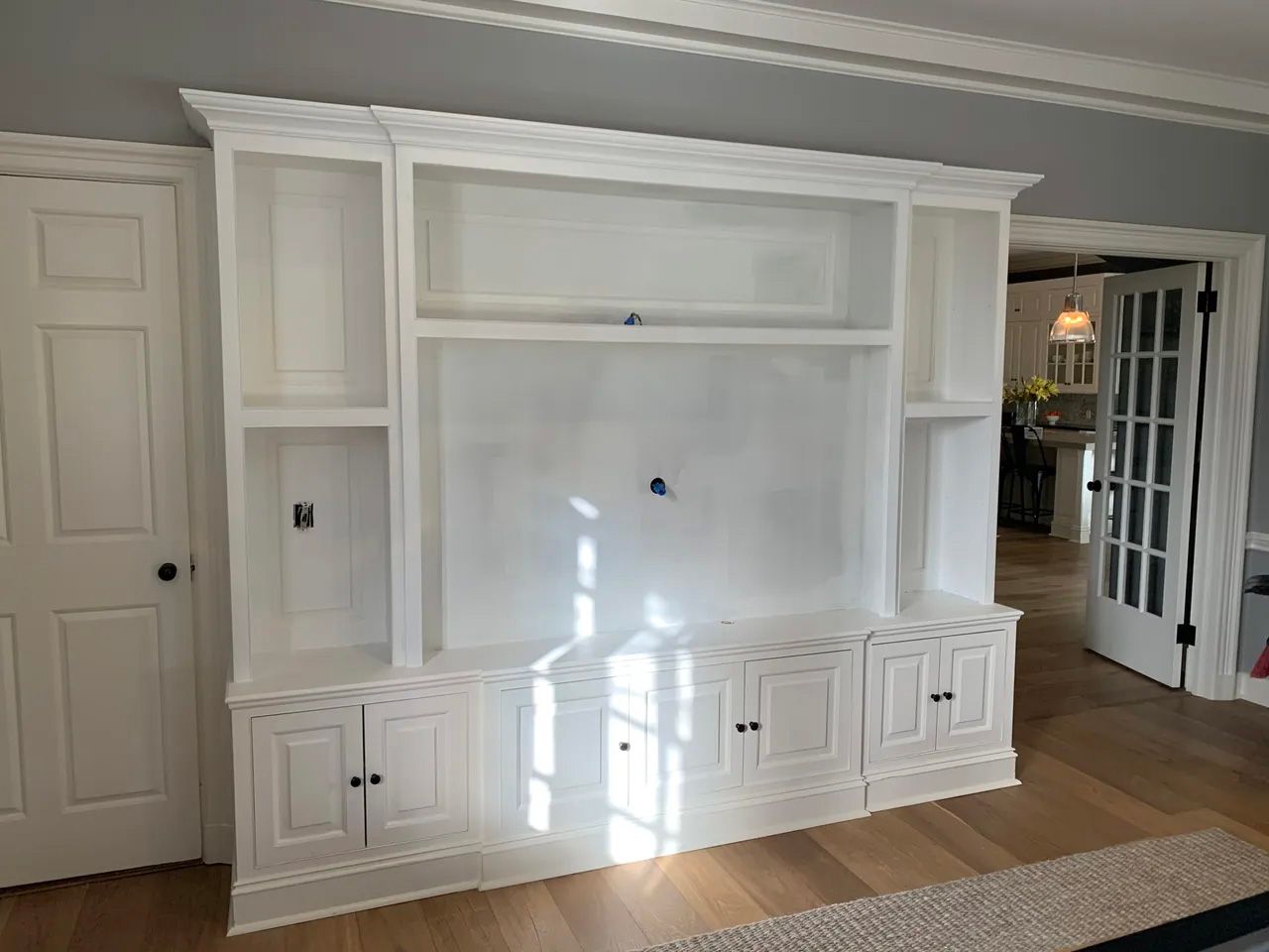 A large white entertainment center in a living room with hardwood floors.