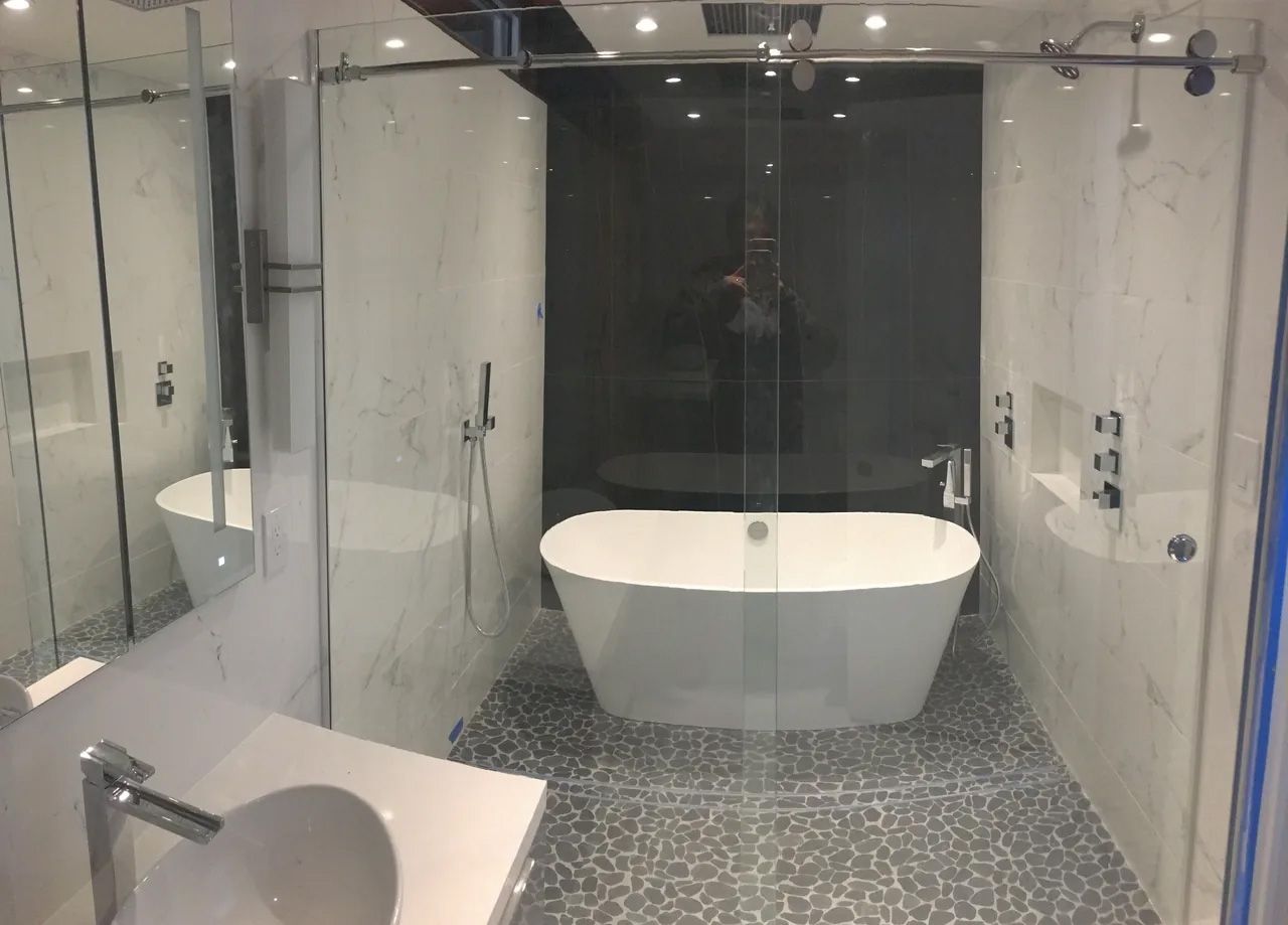 A bathroom with a bathtub , sink , shower and mirror.