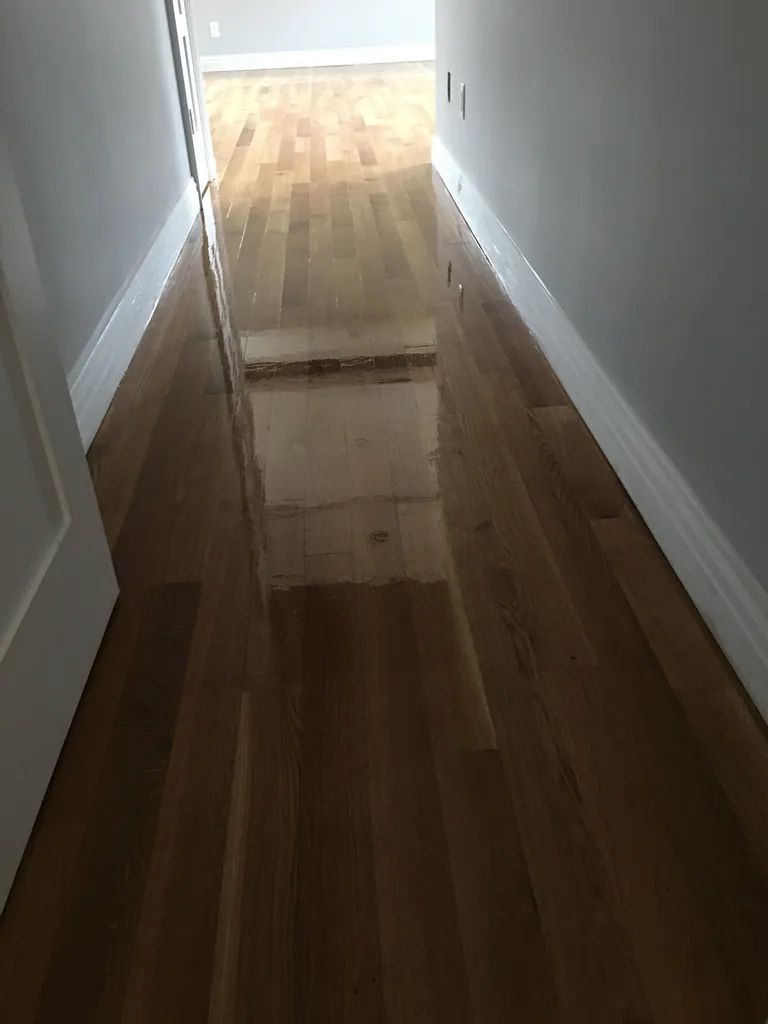 A hallway with a wooden floor and white trim.