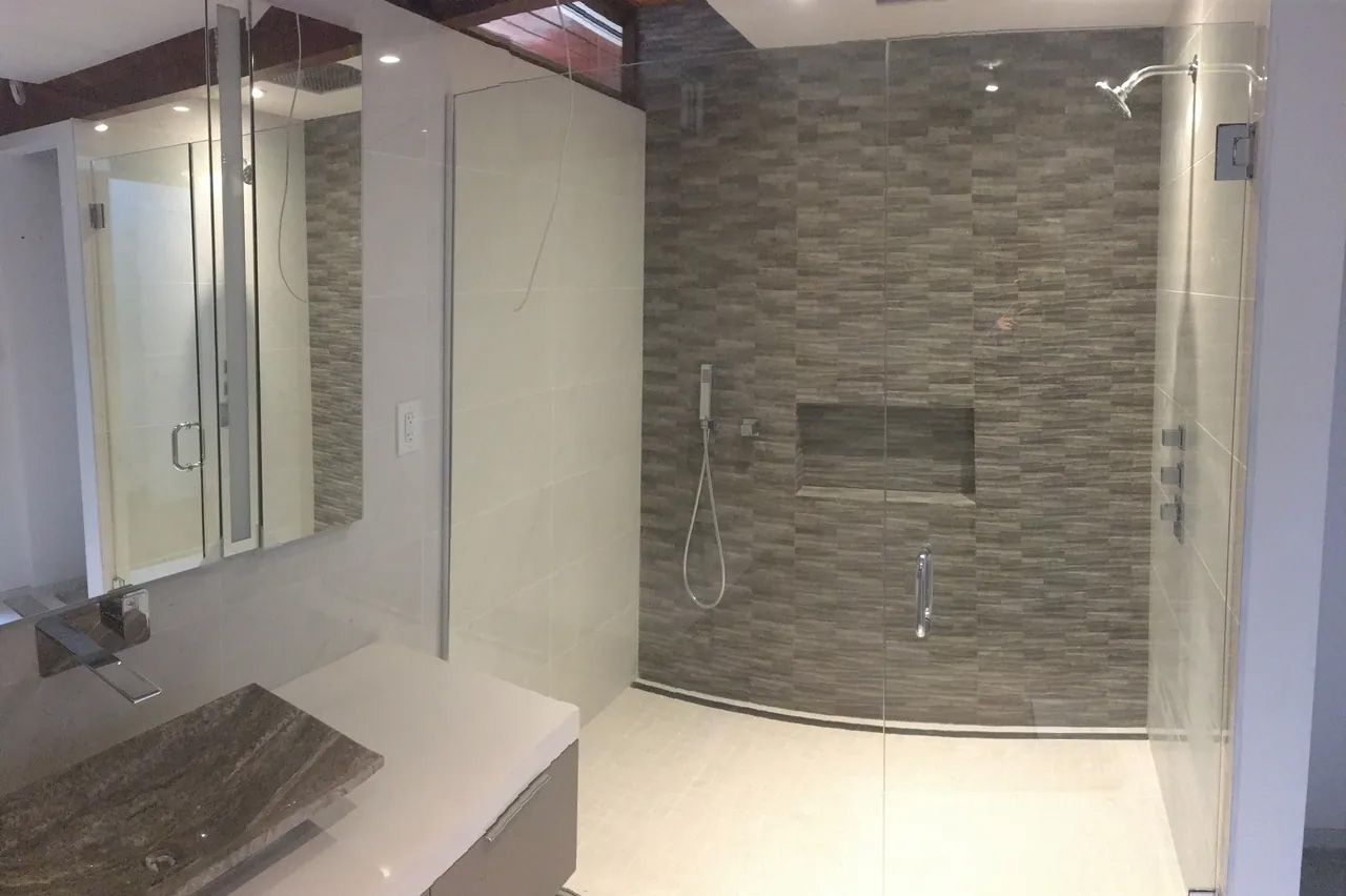 A bathroom with a walk in shower , sink and mirror.