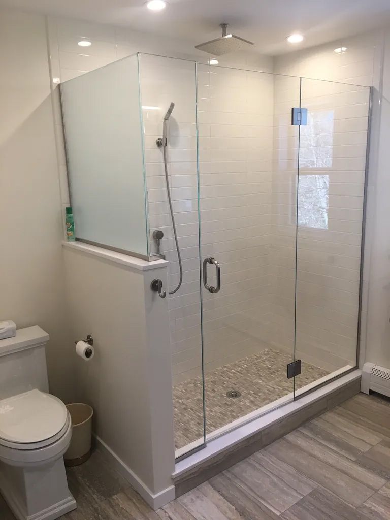A bathroom with a toilet and a walk in shower with a glass door.