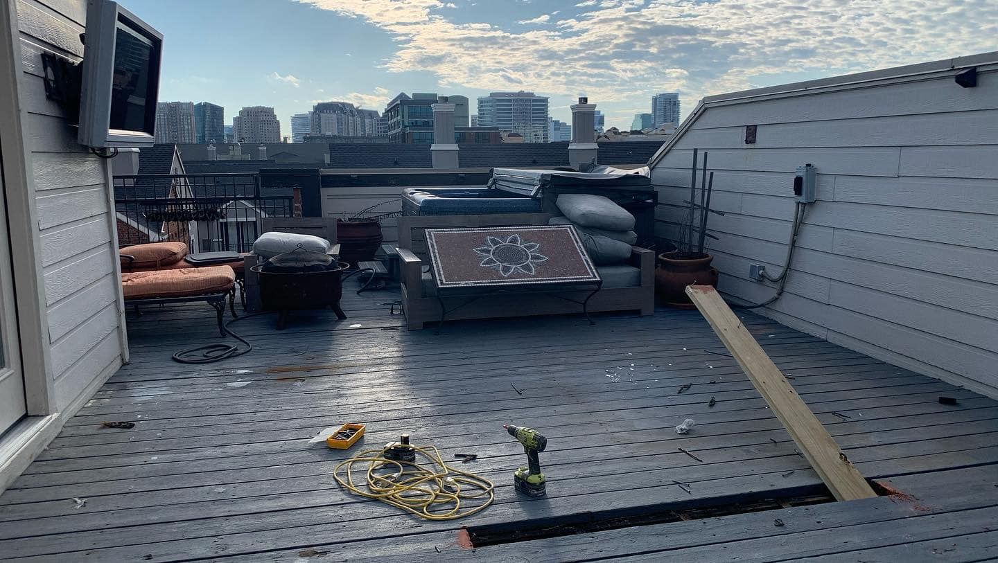 Rooftop patio with furniture, a cityscape in the background, tools on the floor, and a ramp.