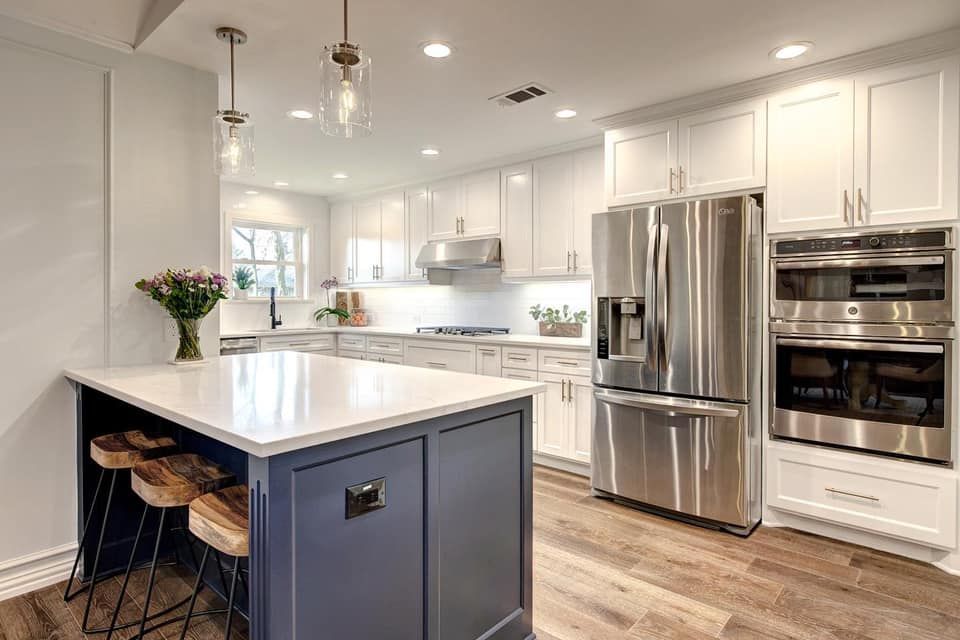 Modern kitchen with white cabinets, stainless steel appliances, and a blue island with wooden stools.