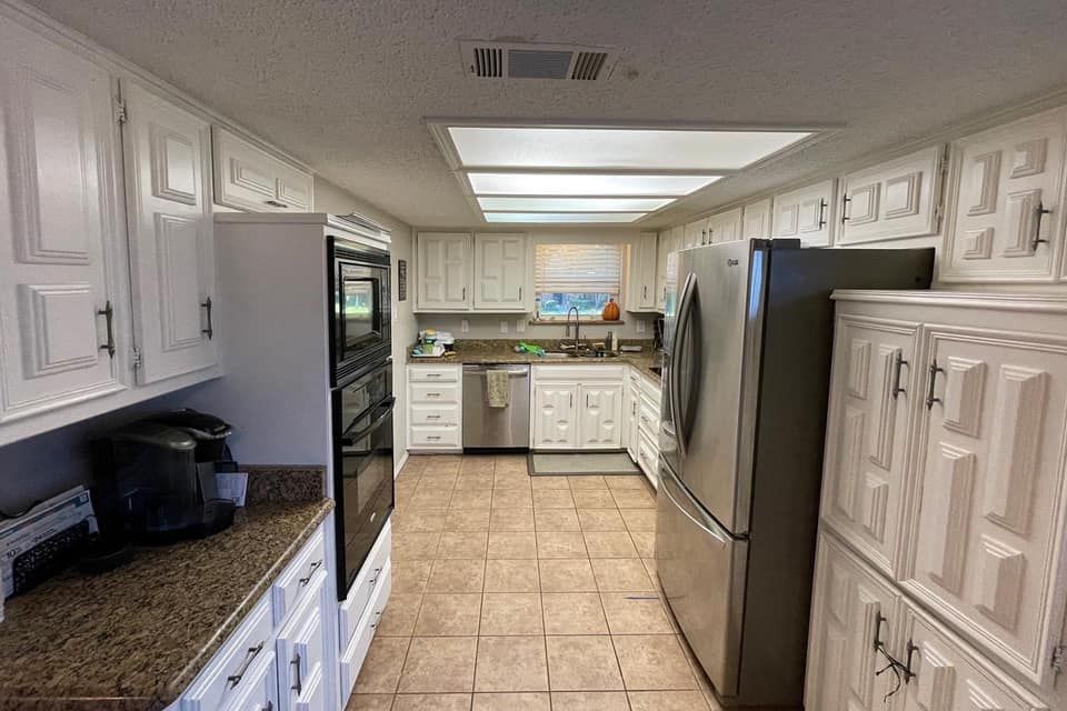 White kitchen cabinets, stainless steel appliances, and brown countertops.