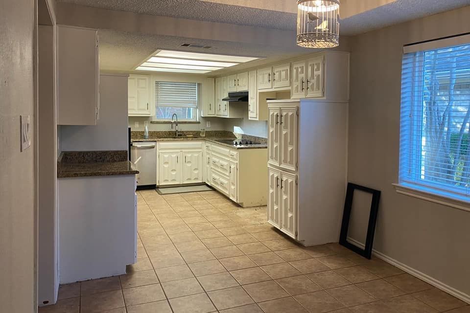 Kitchen with white cabinets, beige tile floor, and a window with blinds.