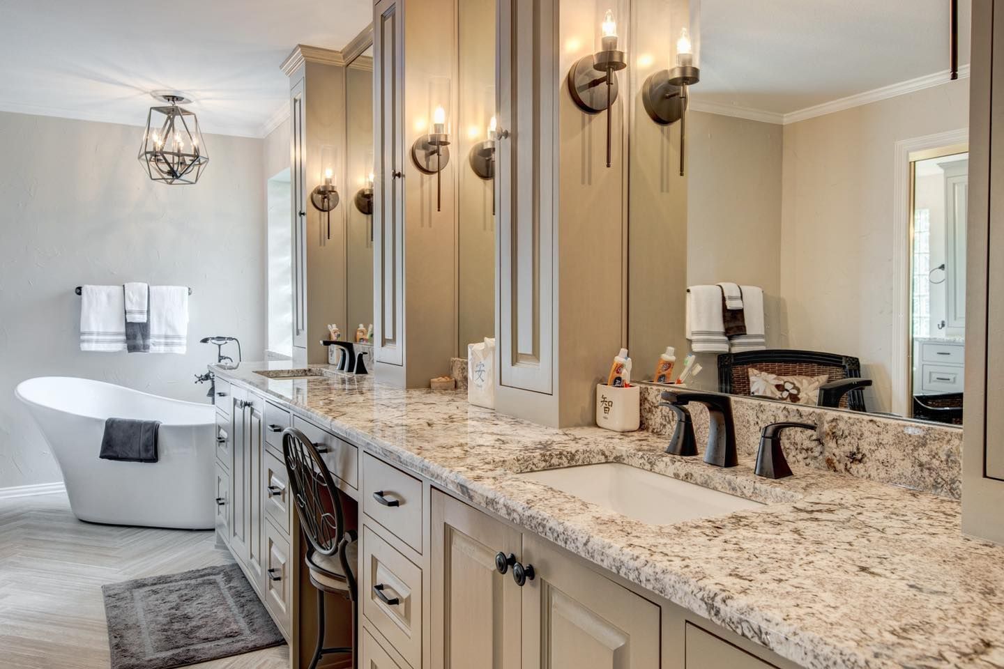 Bathroom with white cabinets, stone countertop, tub, and vanity mirrors.
