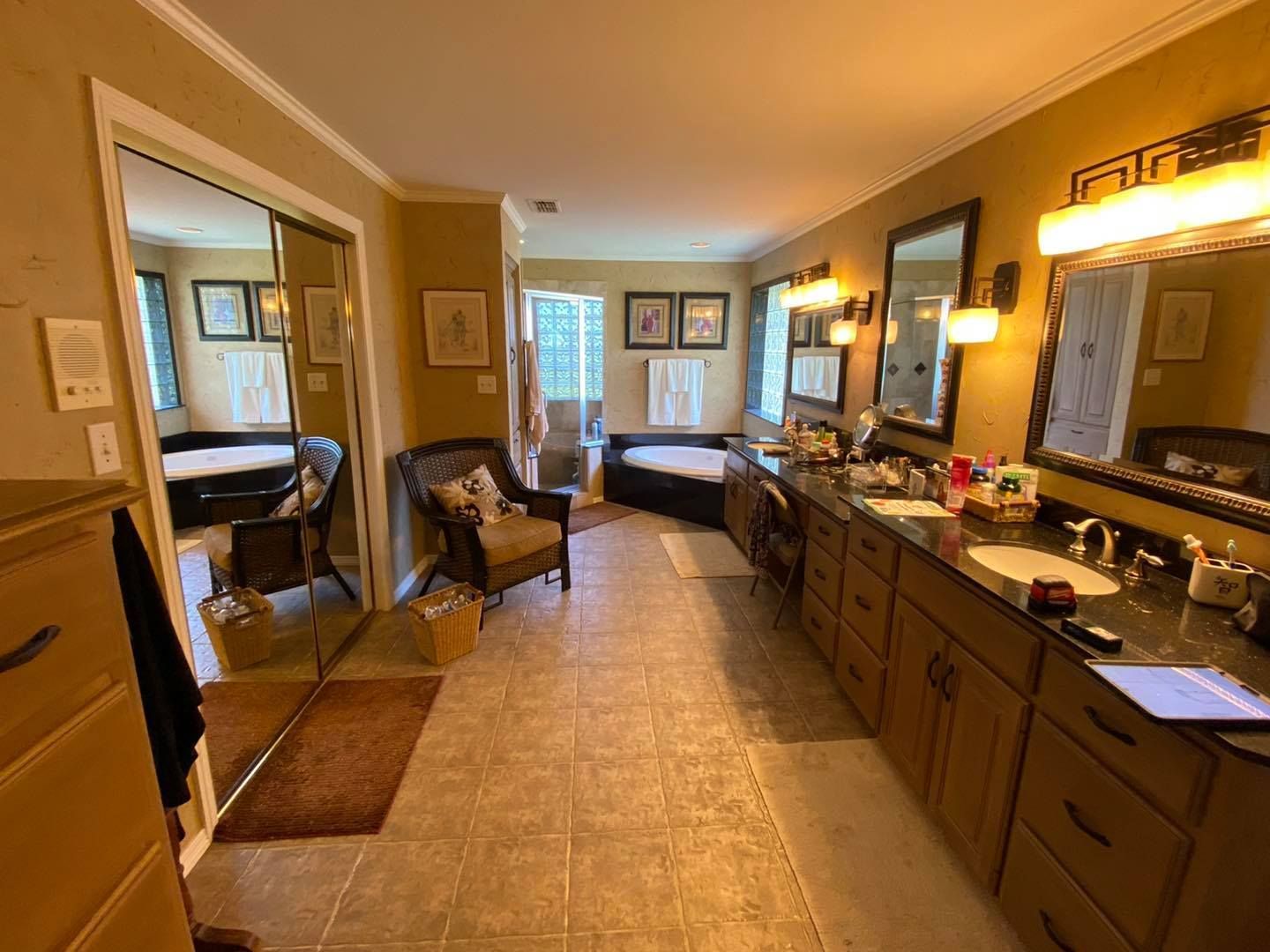 Spacious bathroom with a double sink vanity, two mirrors, and a sunken tub visible.
