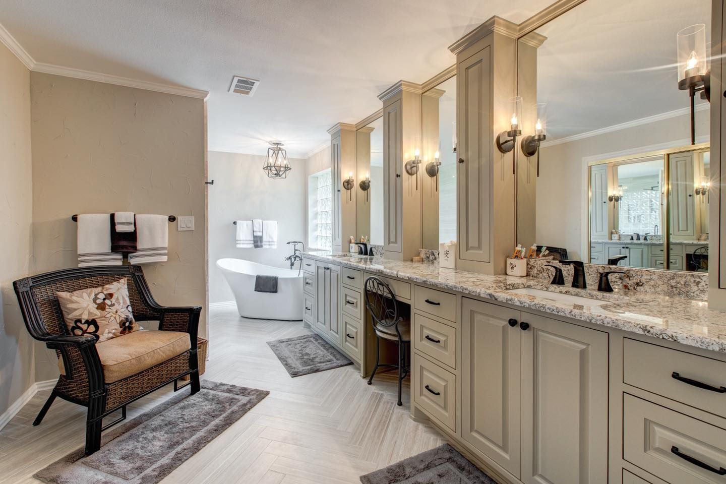 Bathroom with double vanity, bathtub, and wicker chair; neutral colors.