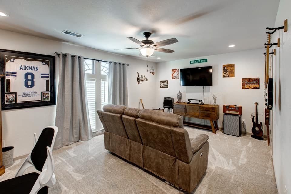 Living room with a brown recliner, TV, guitars, framed jersey, and beige walls.