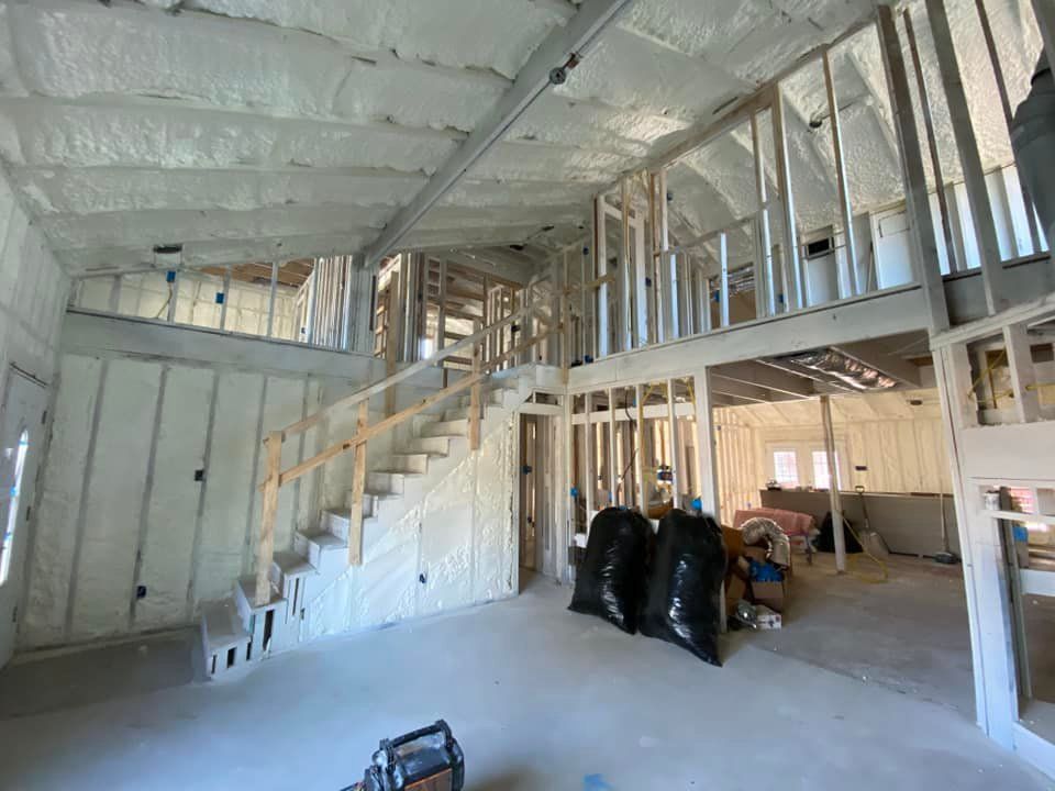 Interior of a house under construction; exposed framing, walls and ceiling covered in spray foam insulation.