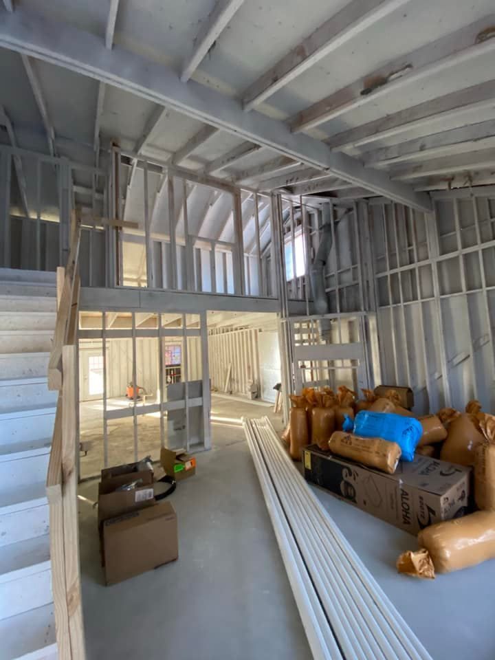 Interior of a building under construction, showing wooden framing, unfinished walls, and building materials.
