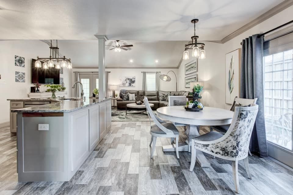 Open-concept living space with kitchen island, dining table, and living room in neutral tones.