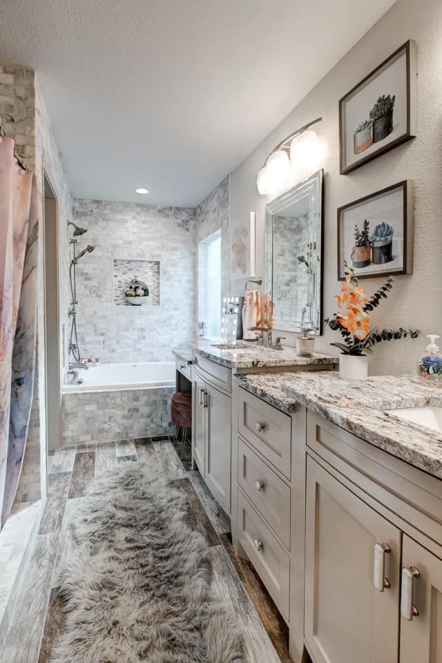 Bathroom with marble tile, double vanity, and framed botanical prints.