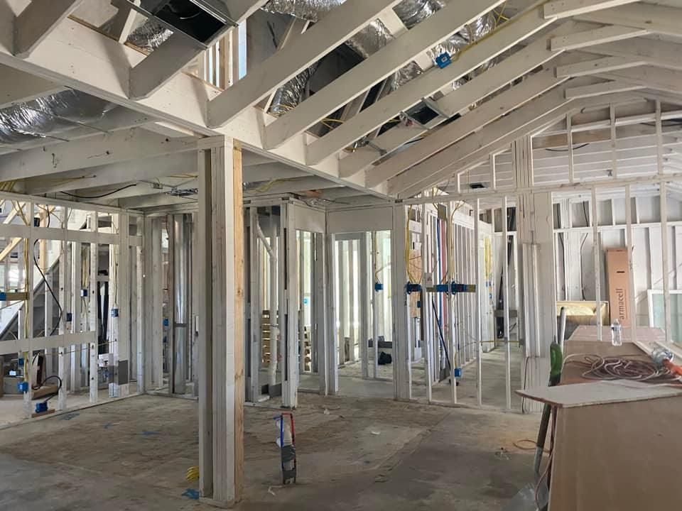 Interior framing of a building under construction, showing wooden studs, beams, and rafters.