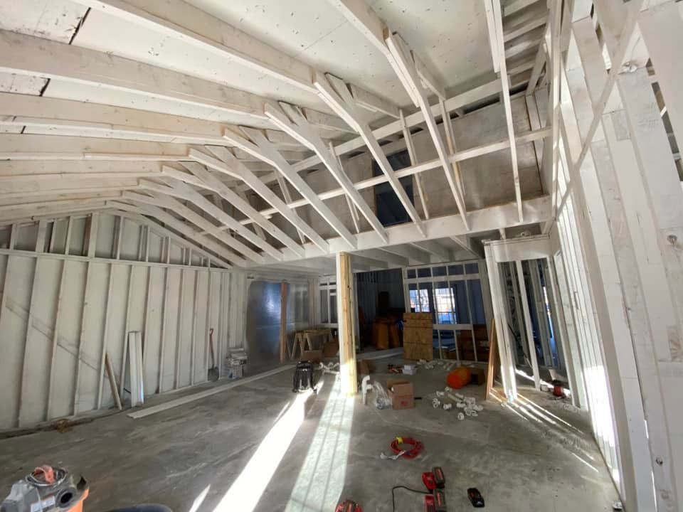 Interior of a building under construction, showing wooden framing and exposed ceiling beams.