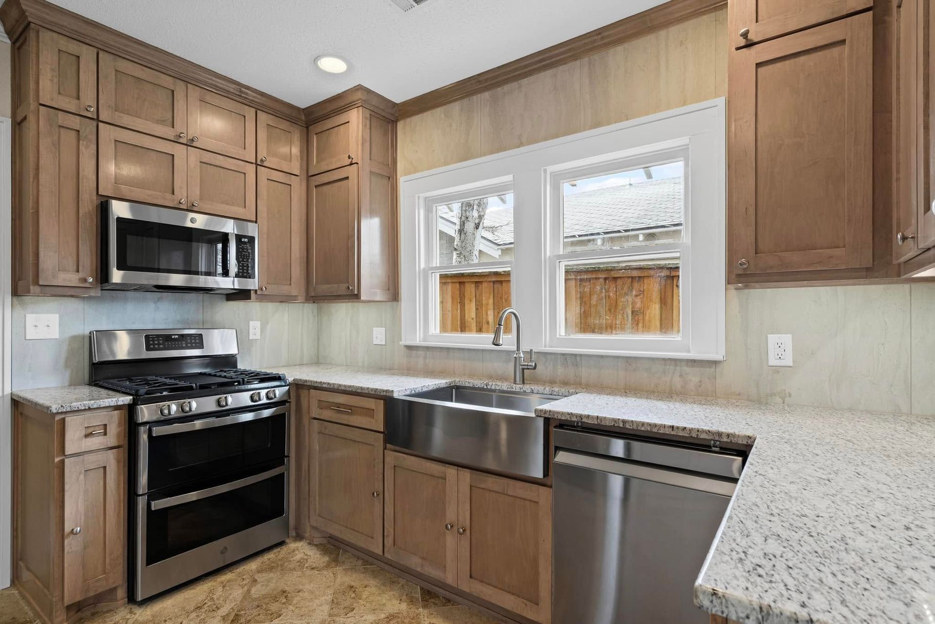 Kitchen with stainless steel appliances, light brown cabinets, and a farmhouse sink.