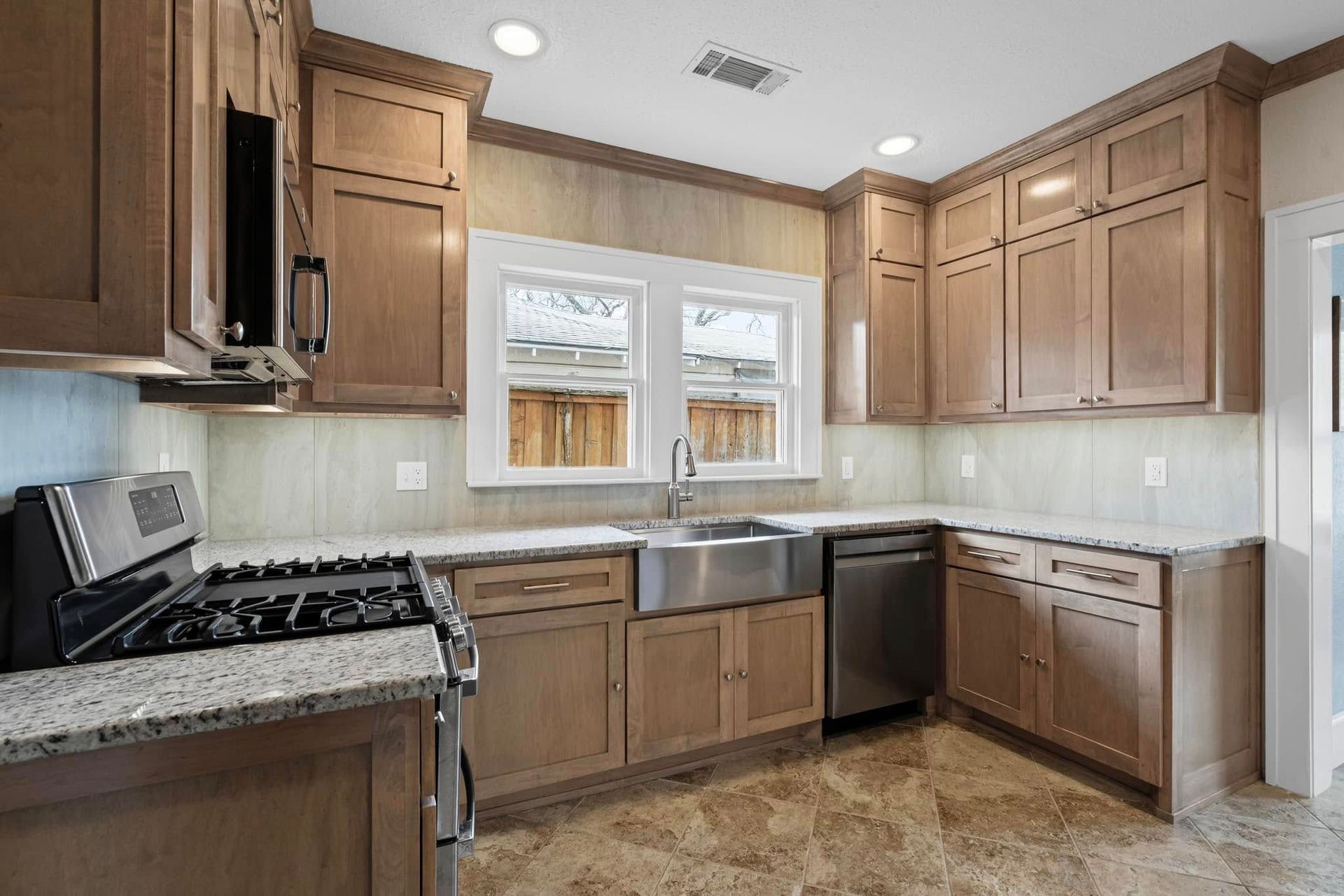 Kitchen with light brown cabinets, stainless steel appliances, and a window above the sink.