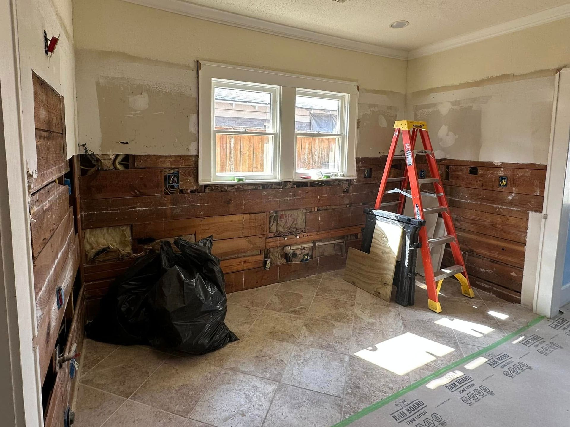 Interior room with exposed wood walls, a ladder, and construction materials.