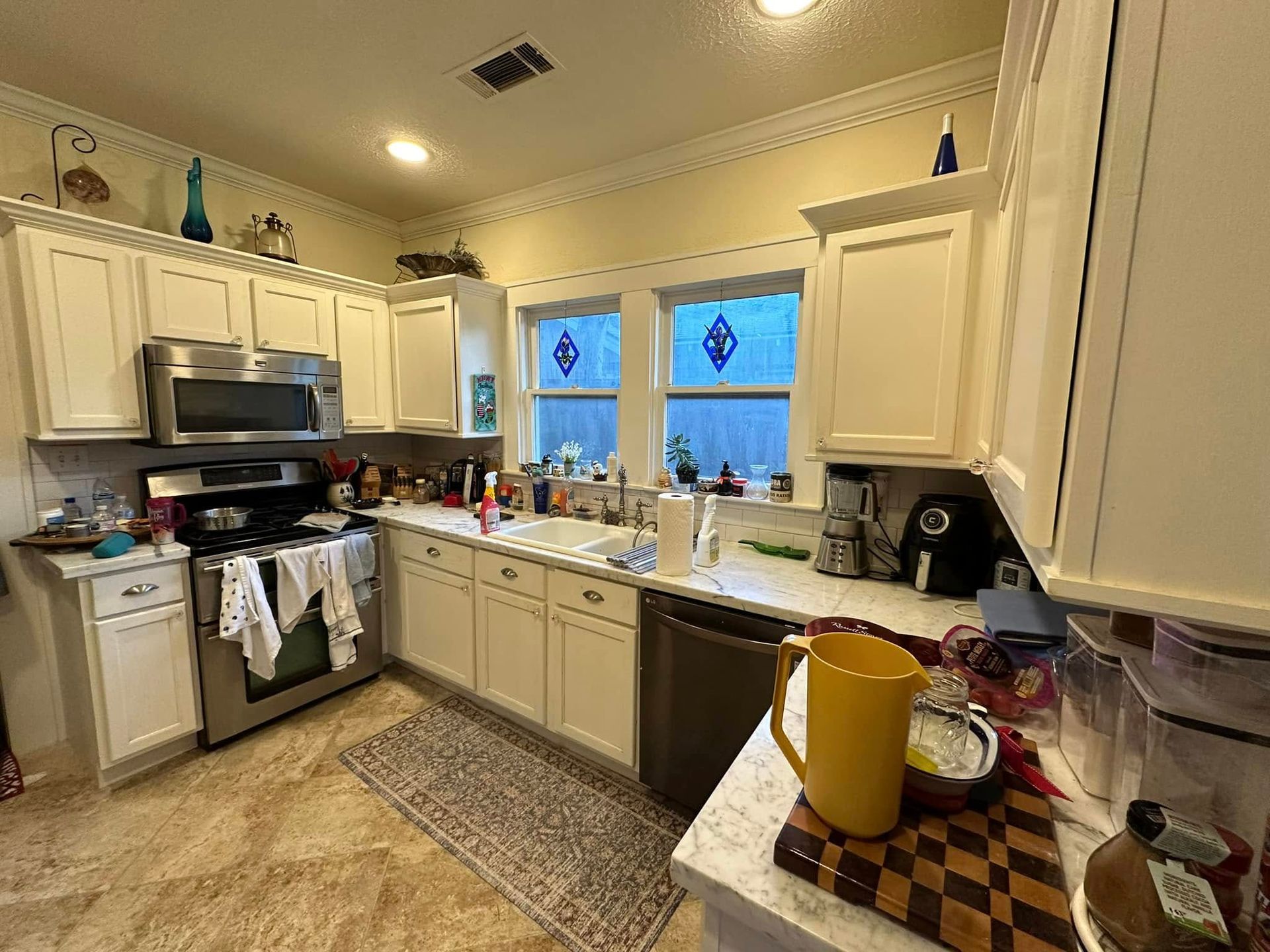 Kitchen with white cabinets, stainless steel appliances, and a window above the sink.