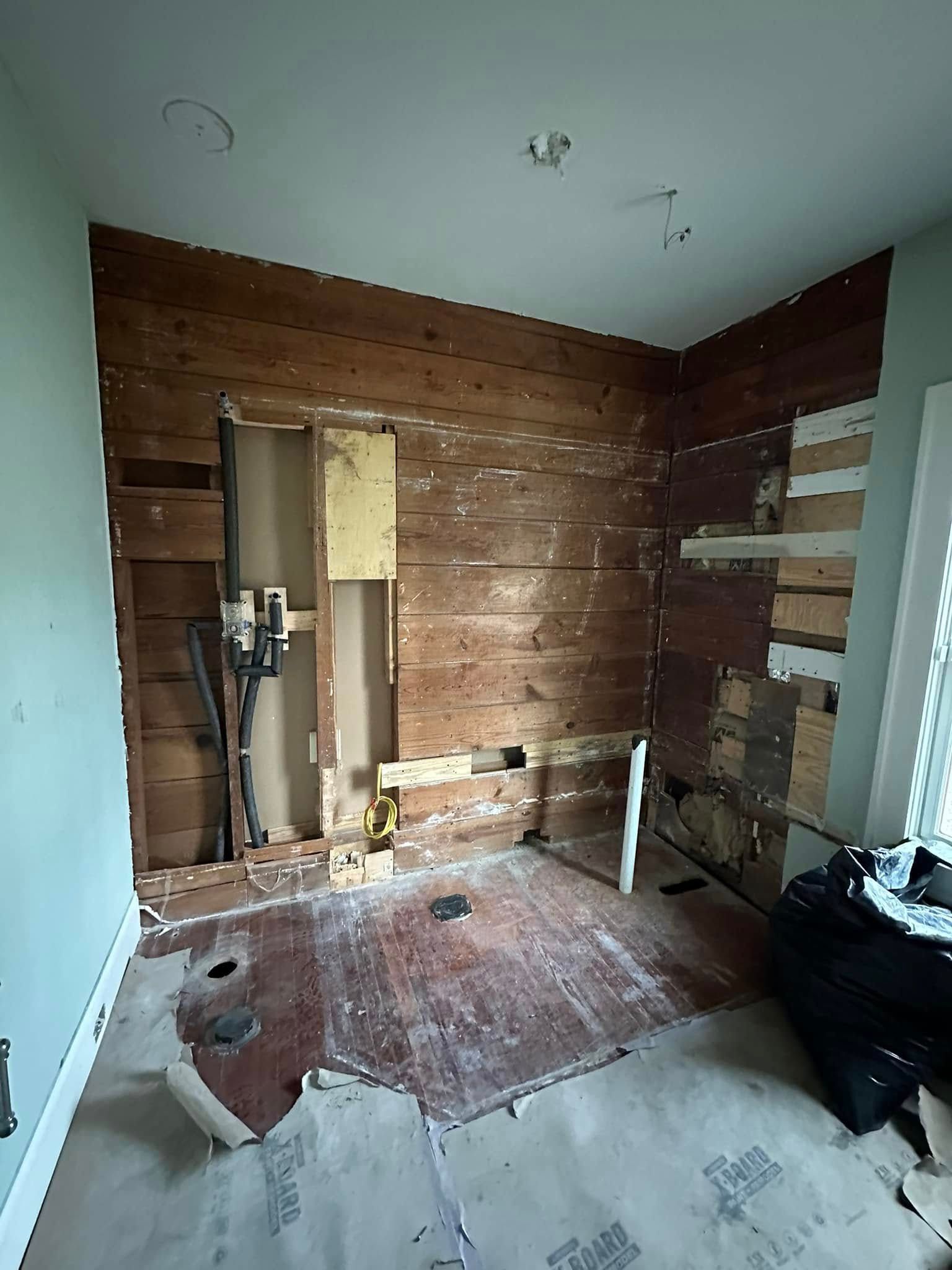 Bathroom undergoing renovation. Exposed wood and electrical, drywall removed, debris on floor.