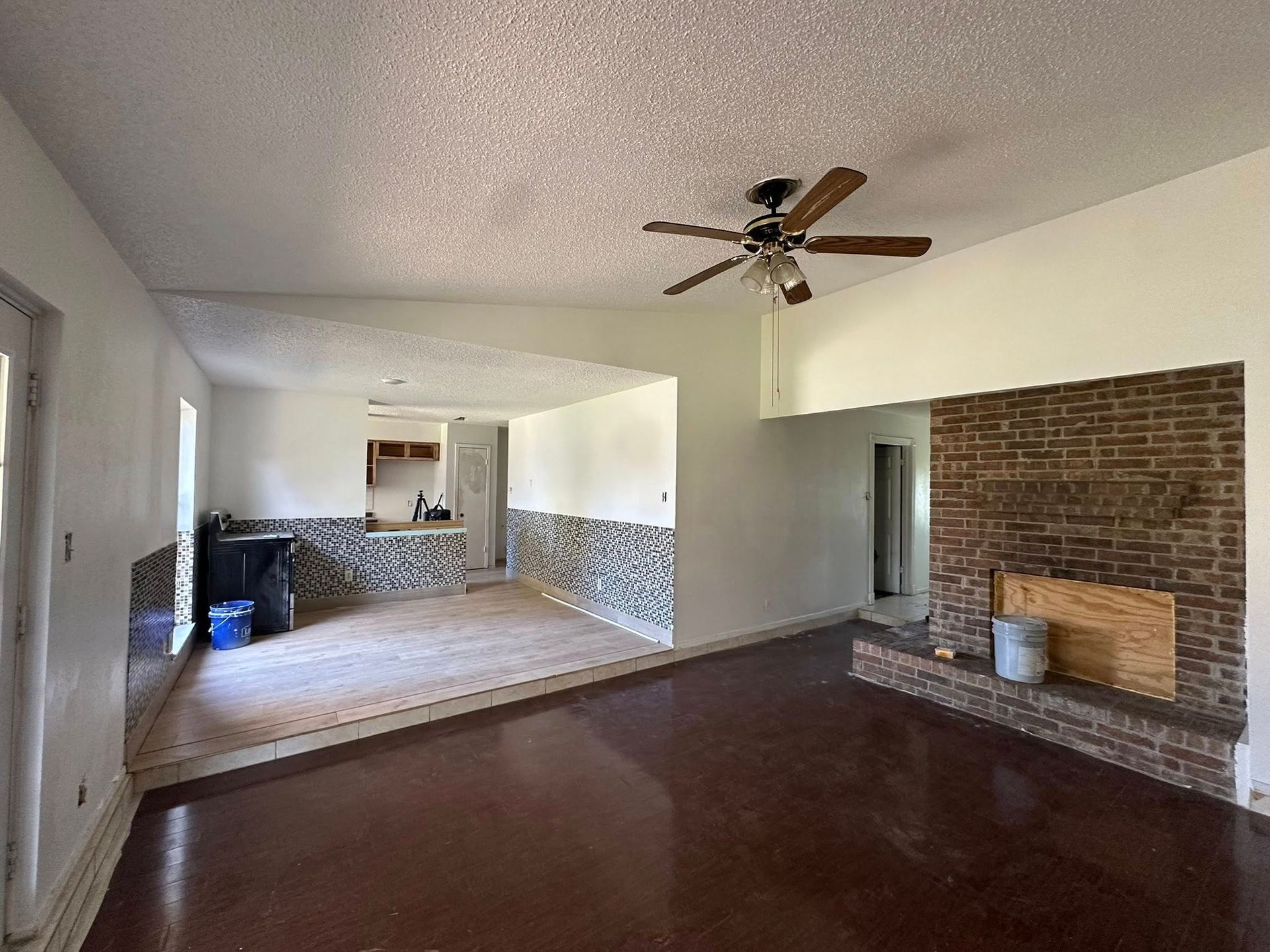 Interior view of a living room with a brick fireplace and a dark brown floor.
