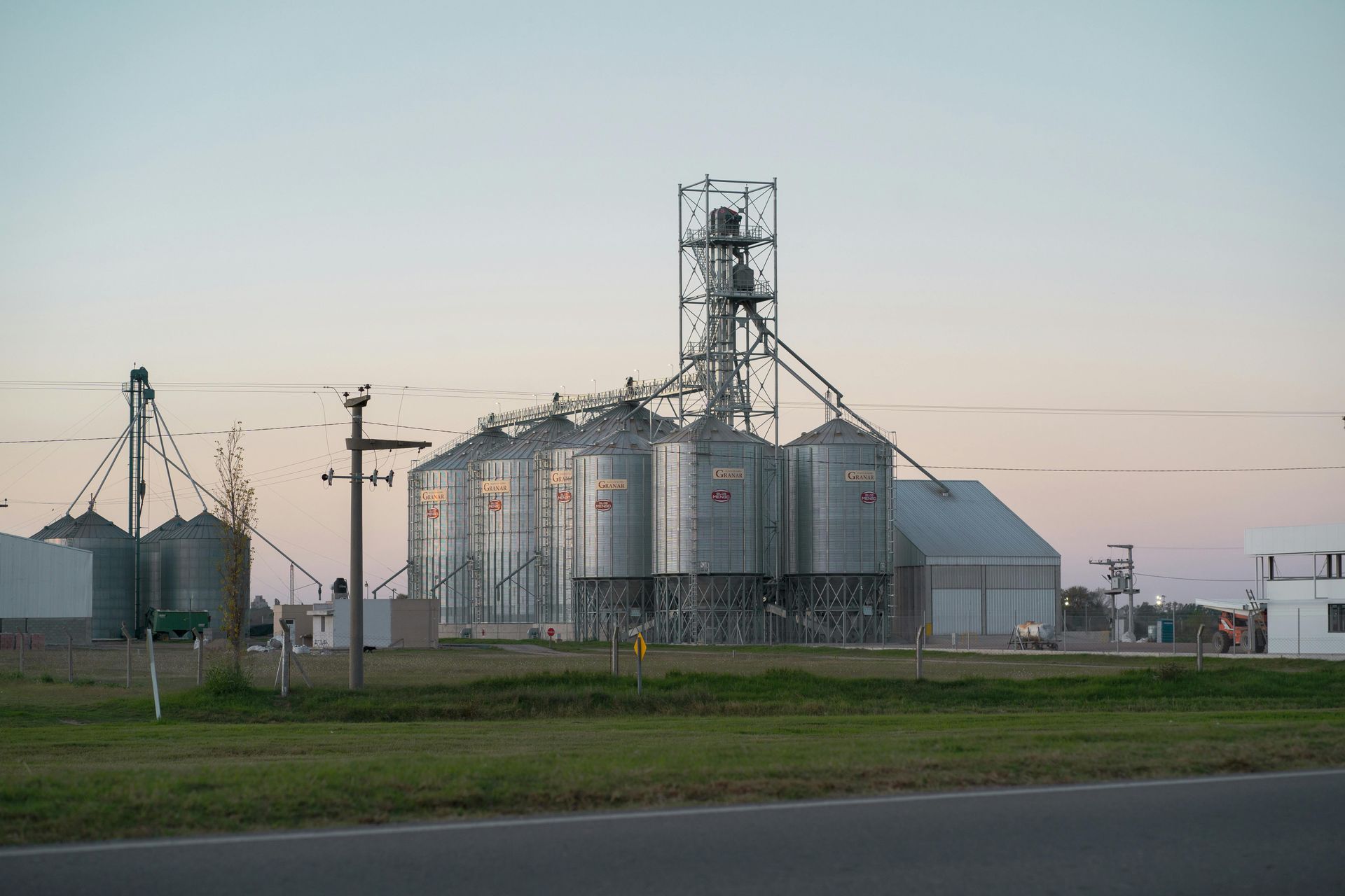 Grain silos and processing facility under a pale sky.