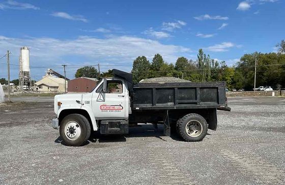 A dump truck is parked in a gravel lot.