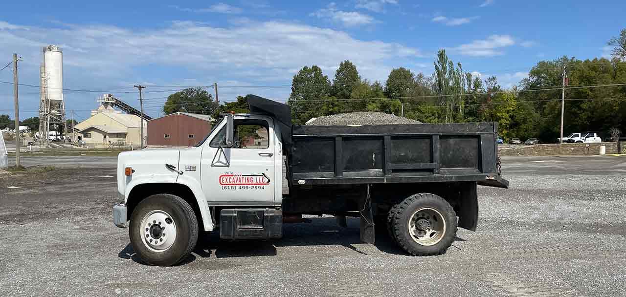 A dump truck is parked in a gravel lot.