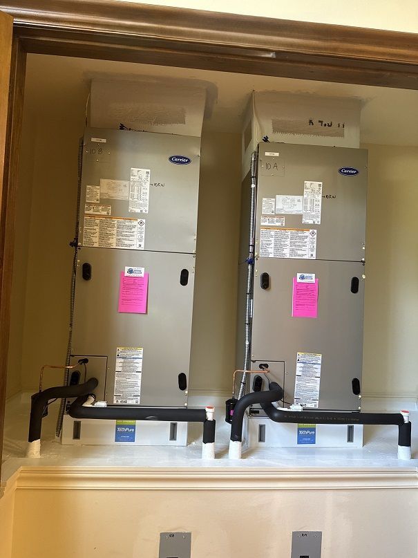 Two Carrier HVAC units installed in a closet. Black pipes connect to the units.