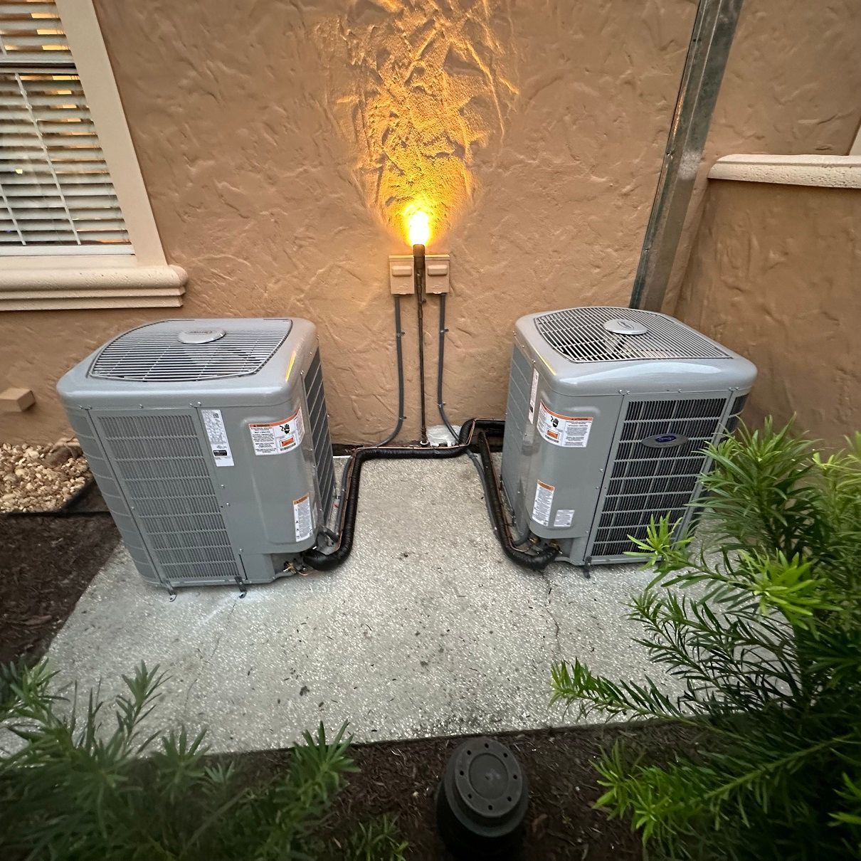 Two AC units outside a building with electrical arcing from the power supply.