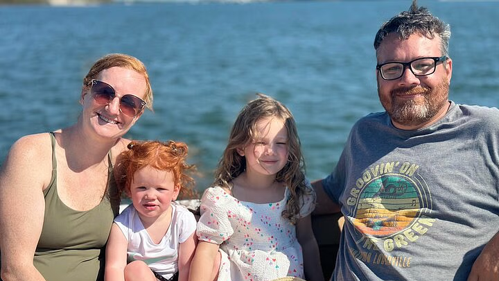 A family of four smiles on a boat.
