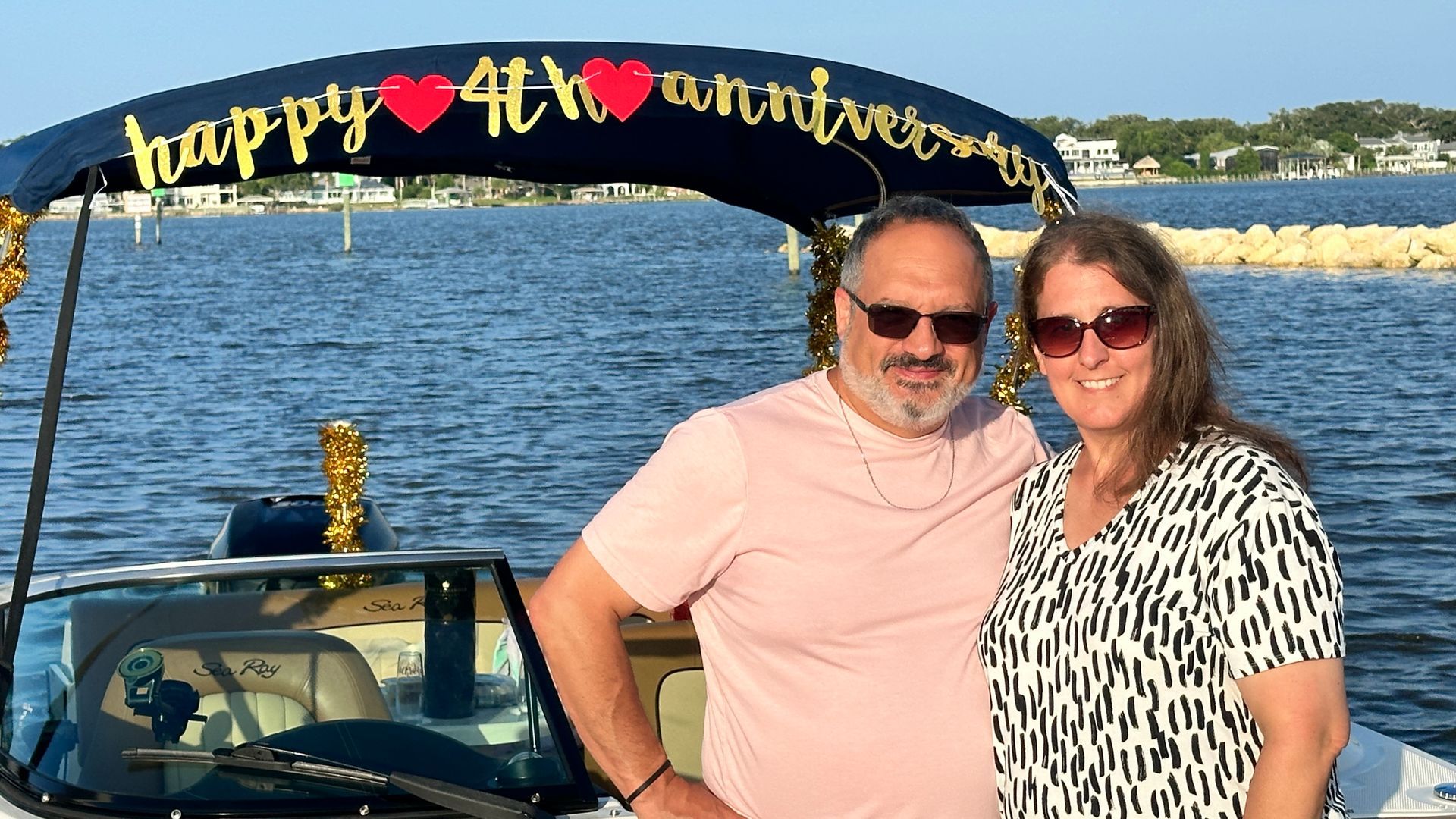 Couple celebrating their 4th anniversary on a boat; they are smiling with the banner 