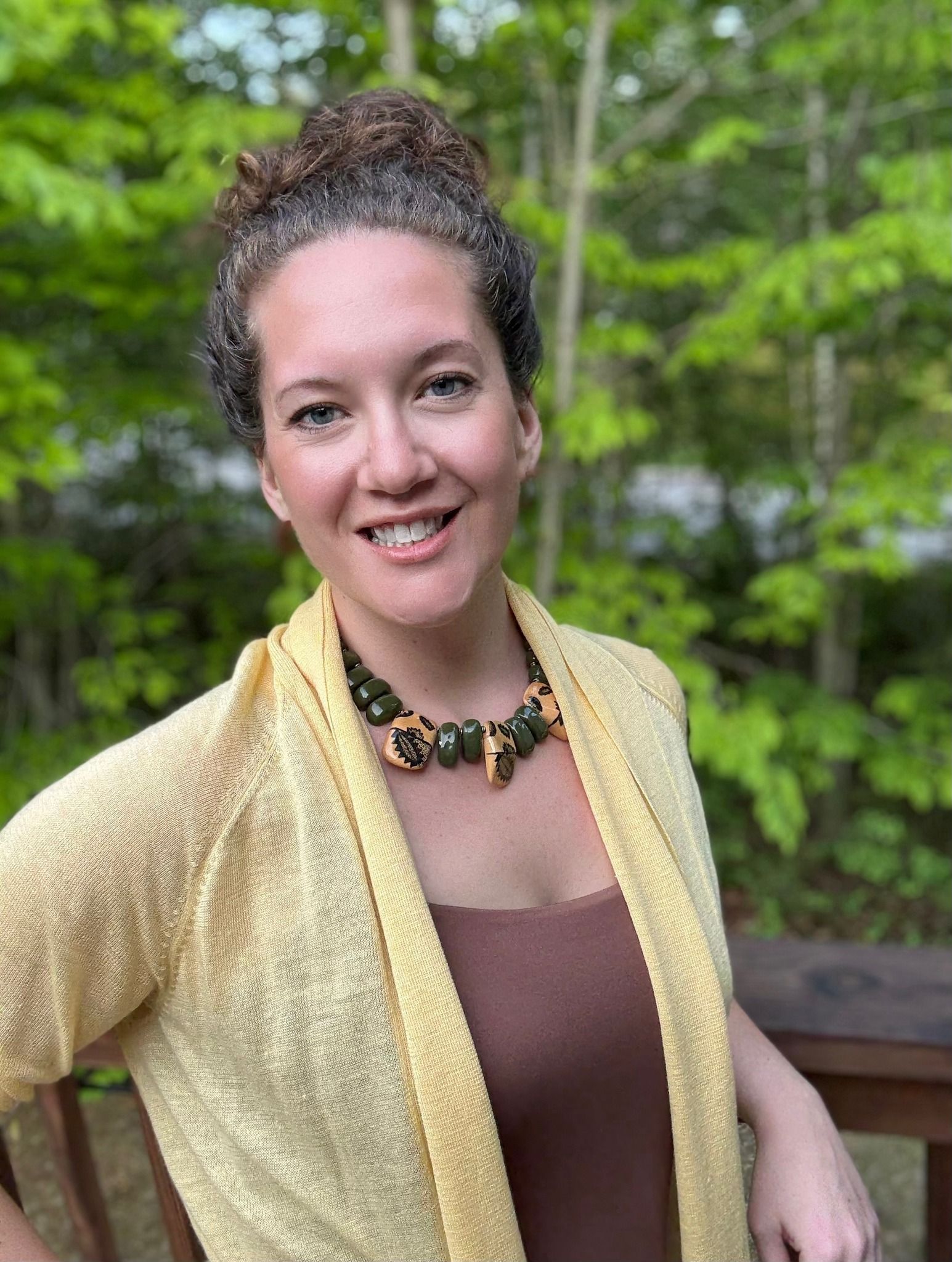A woman is sitting at a desk with a laptop and a vase of flowers.