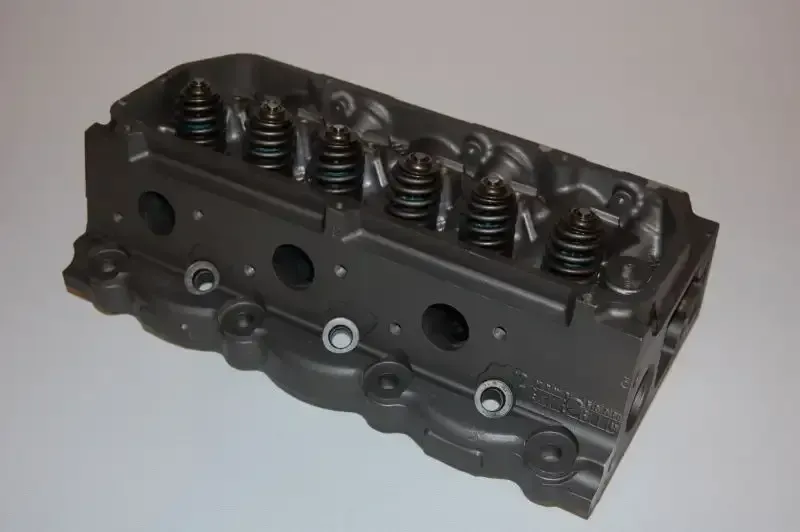 A close up of a cylinder head on a white surface