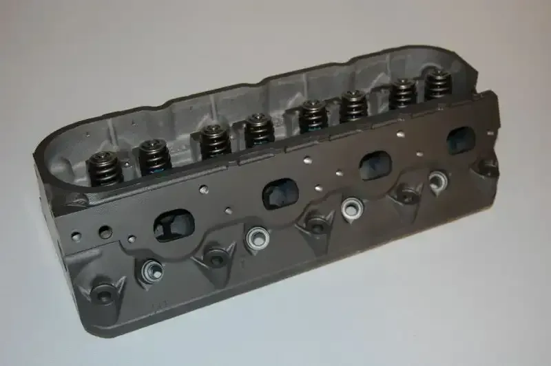 A close up of a cylinder head on a white surface