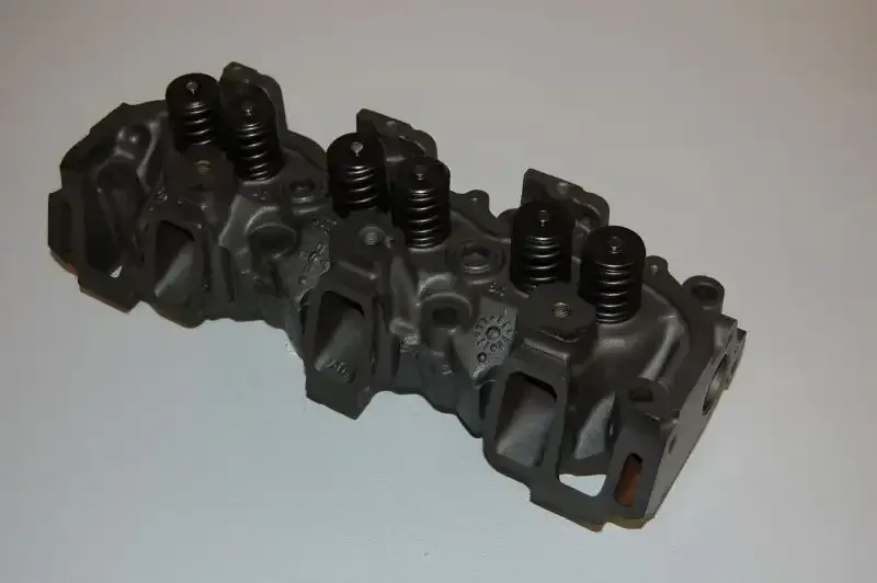 A close up of a cylinder head on a white surface