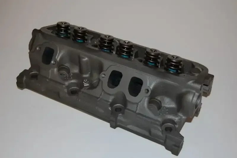 A close up of a cylinder head on a white surface