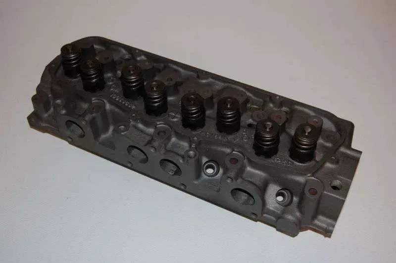 A close up of a cylinder head on a white surface