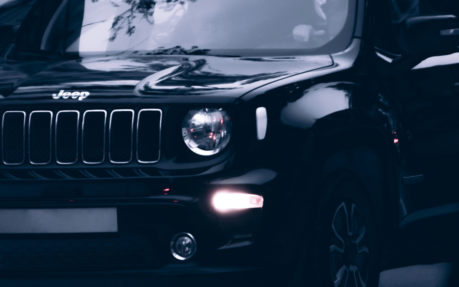A black jeep renegade is parked in a dark parking lot.