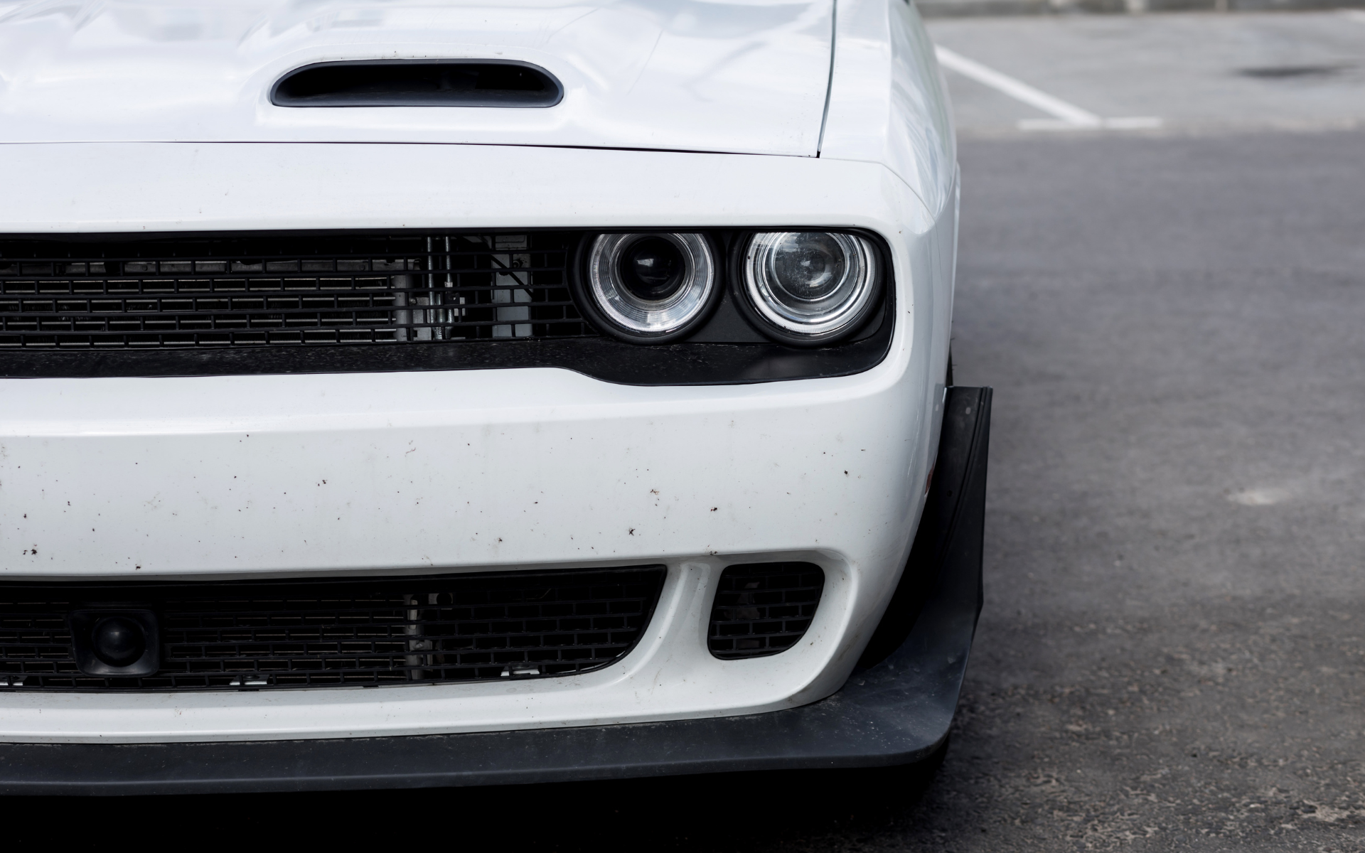 A white dodge challenger is parked in a parking lot.