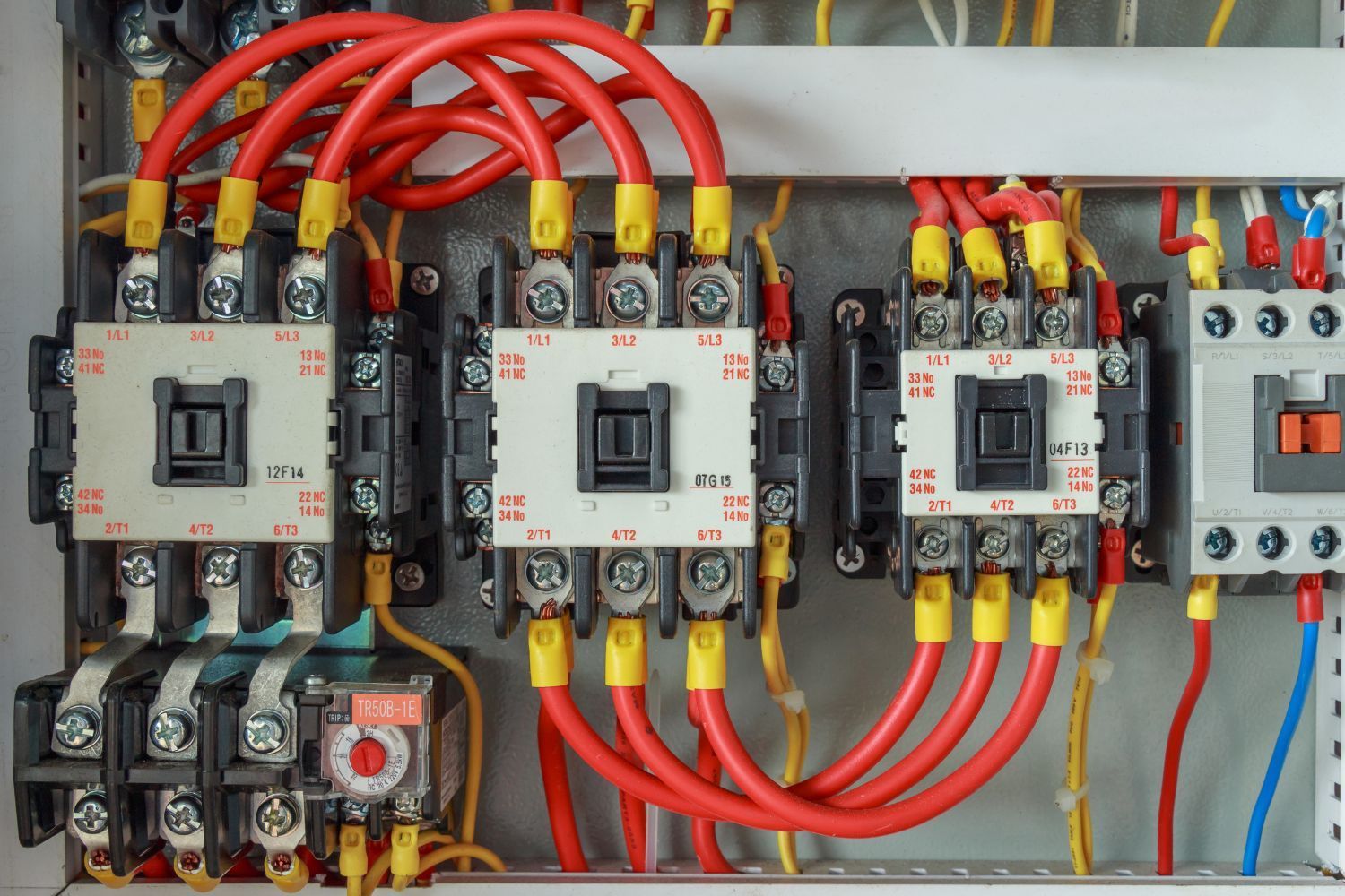 Electrical control panel with red and yellow wires connected to contactors and circuit breakers.