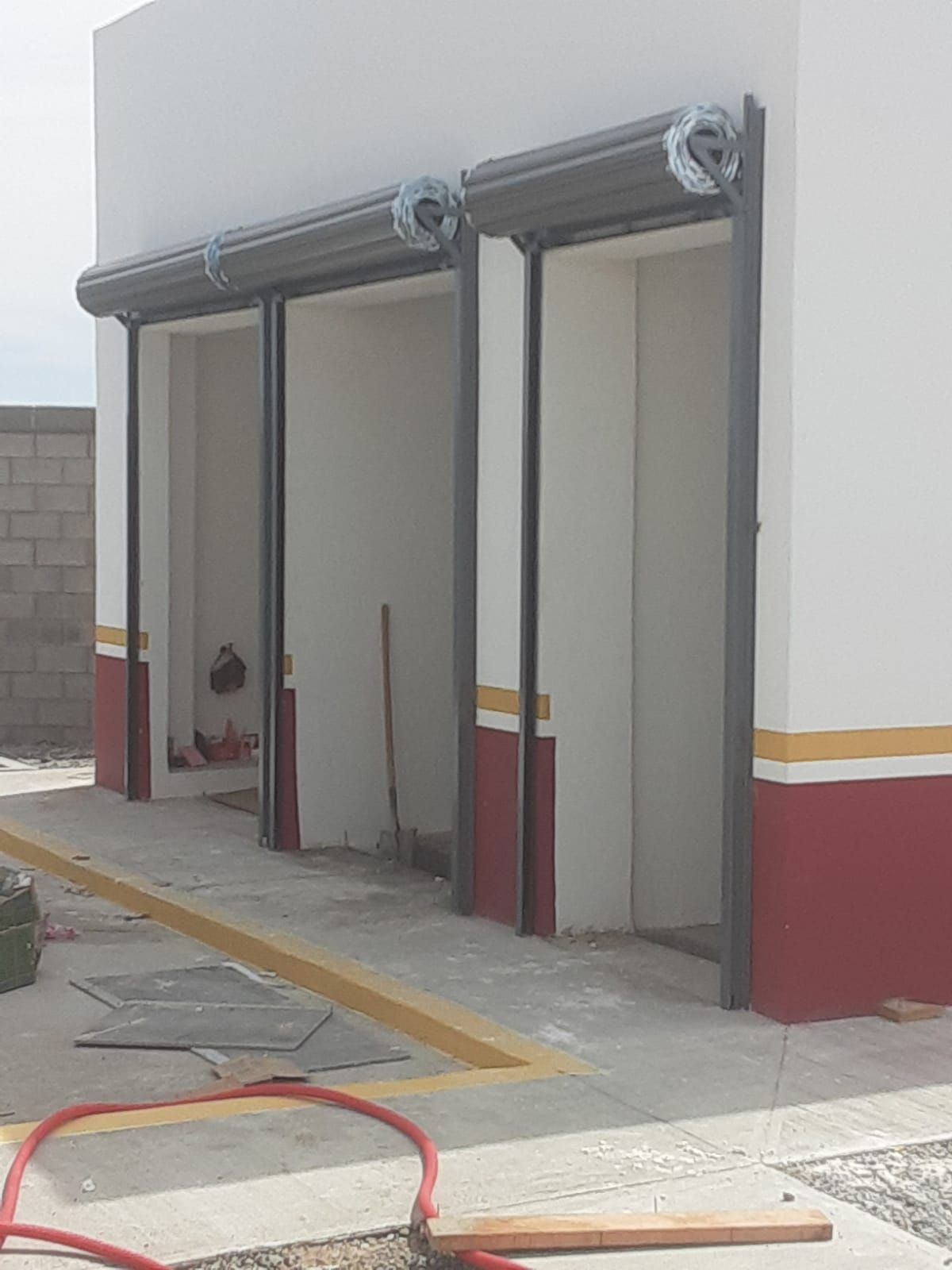 Un edificio blanco con adornos rojos y amarillos y una manguera frente a él.