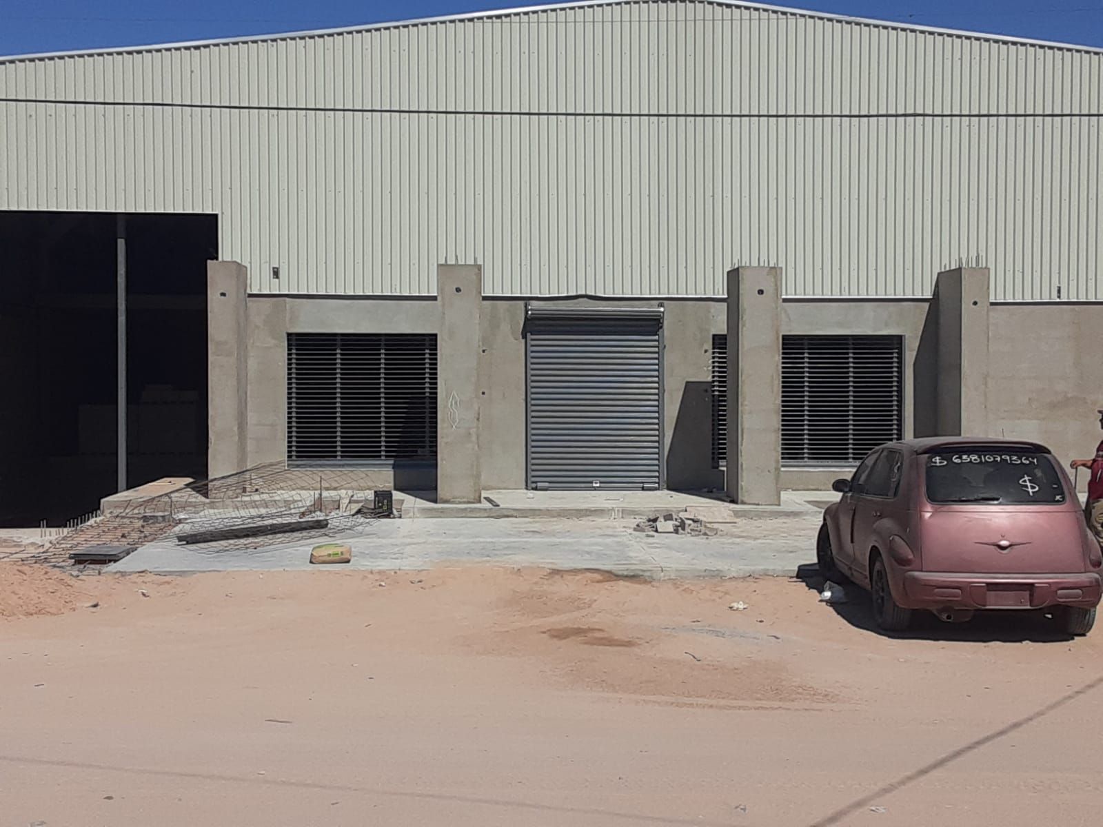 Un coche rosa está aparcado frente a un edificio en construcción.