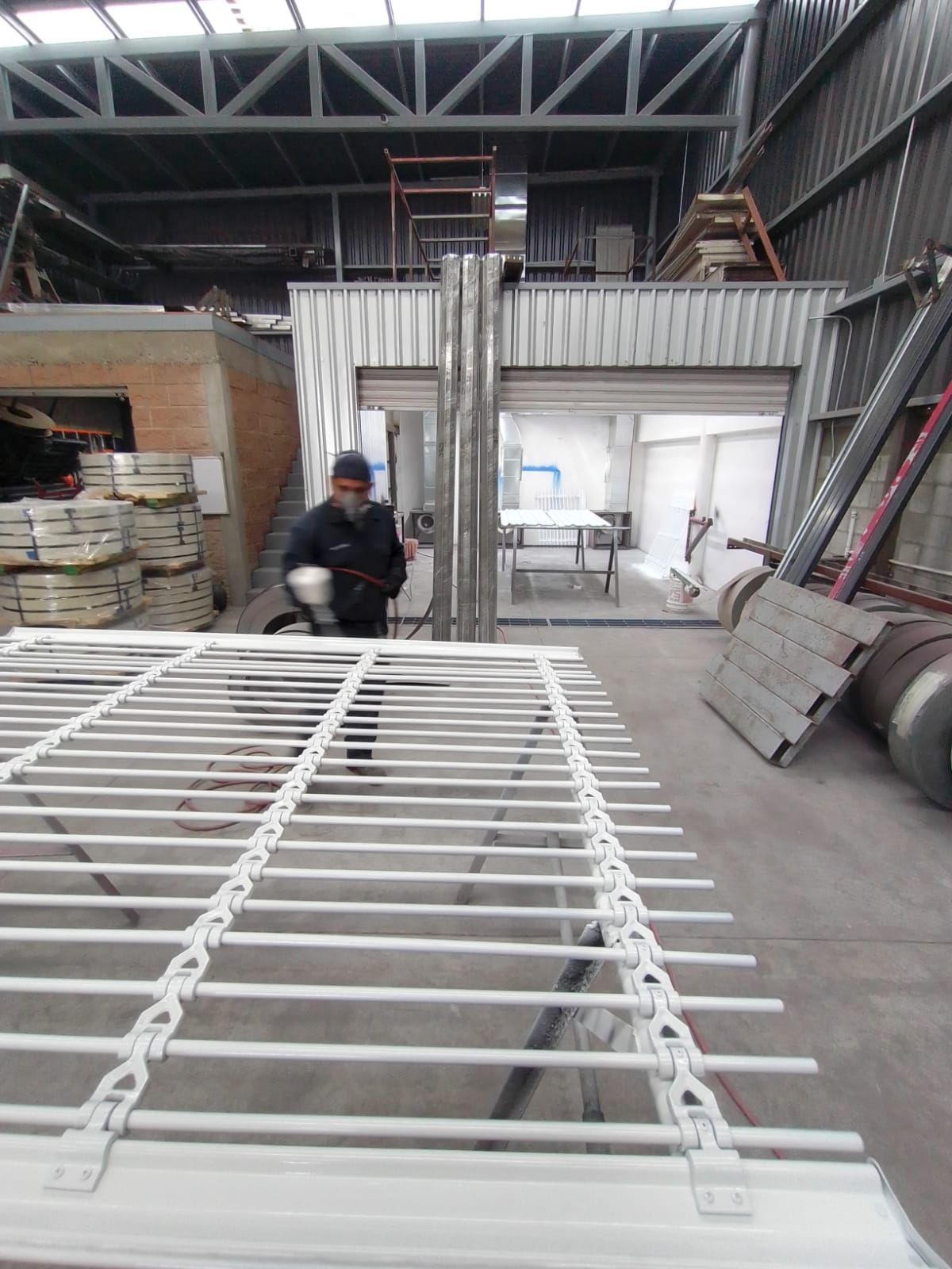 Un hombre trabaja en una estructura metálica en un almacén.